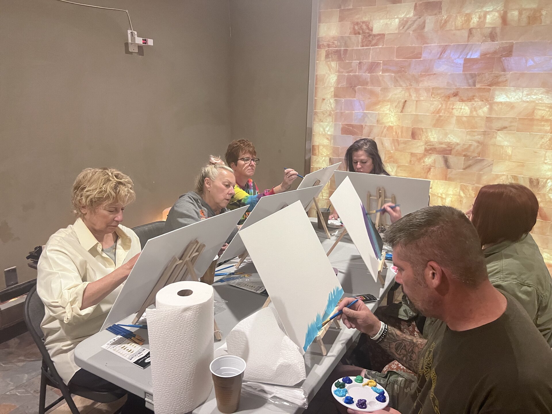 A group painting together beside the illuminated salt wall